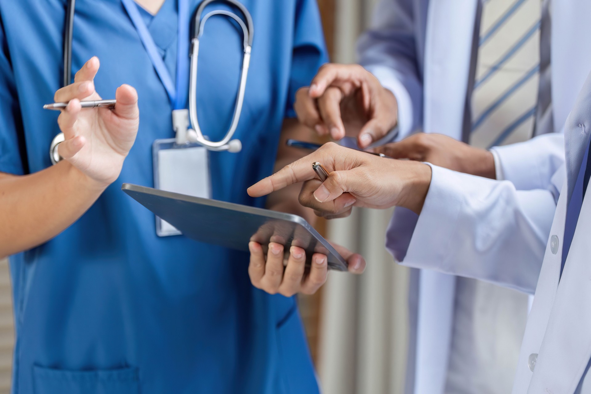 Doctor collaborating with team using tablet in medical consultation